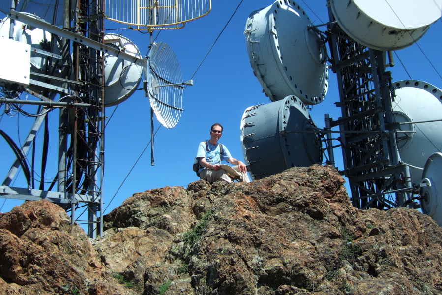 Bill B. sits atop North Peak amidst the antenna towers.