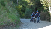 A group of bikers walking up the steep gravel section.