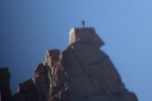 A climber stands upon the summit of Cathedral Peak.