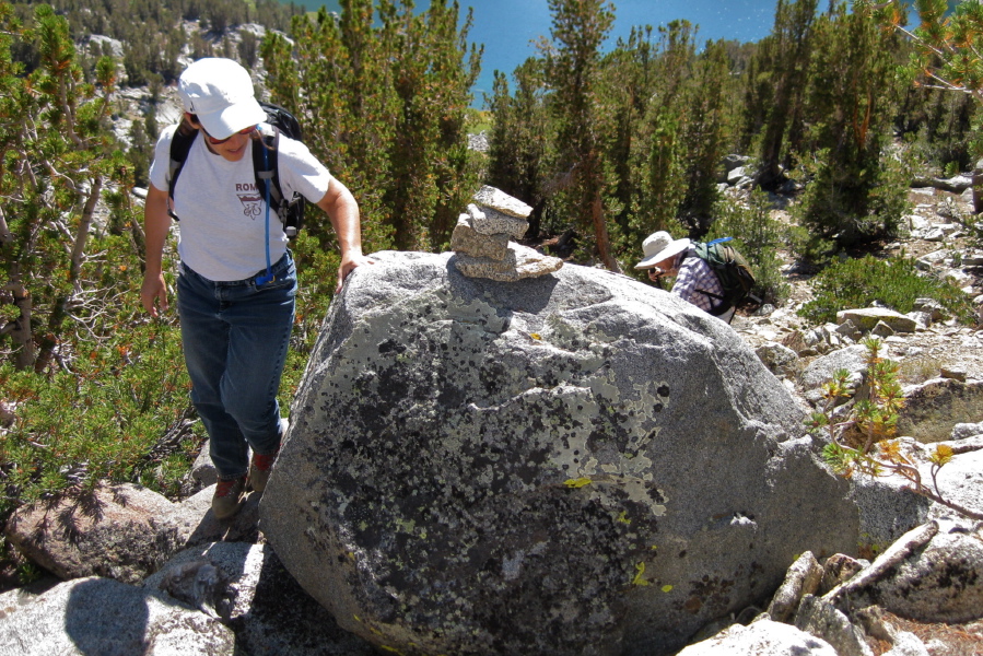 Stella passes a cairn; David follows.