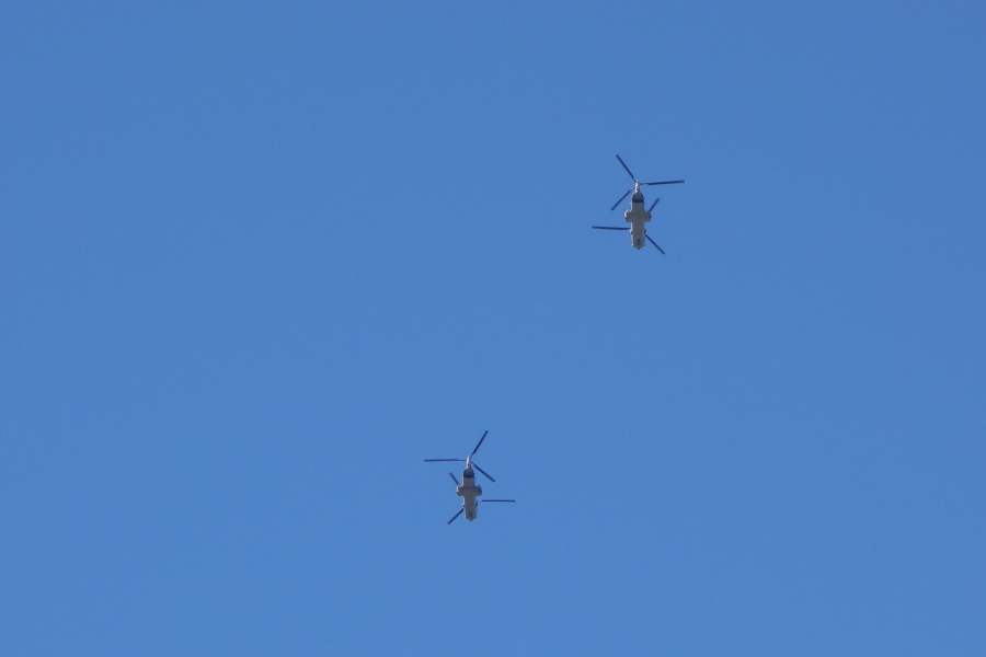 Transport helicopters pass overhead.