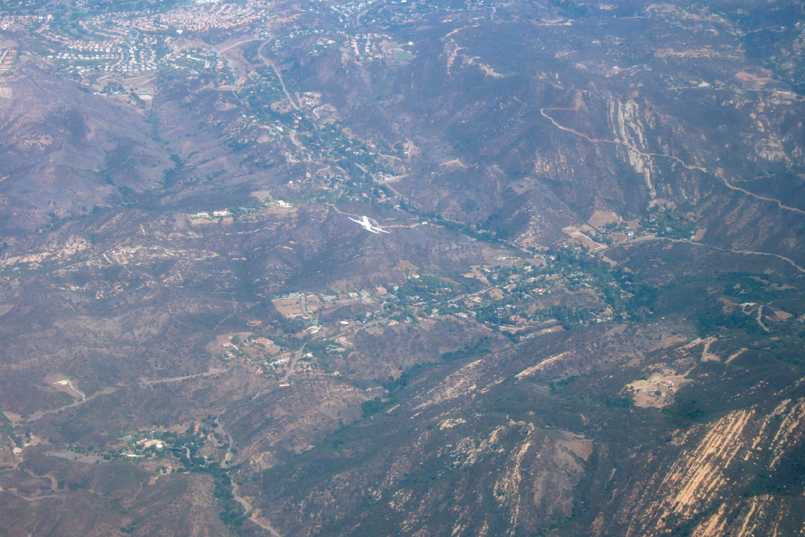 Another plane passes underneath above the Malibu Hills.