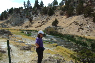 Stella stands at the shore of Hot Creek.