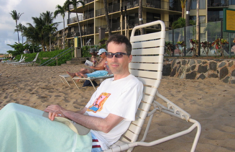 Bill relaxes on a lounge chair on the beach.