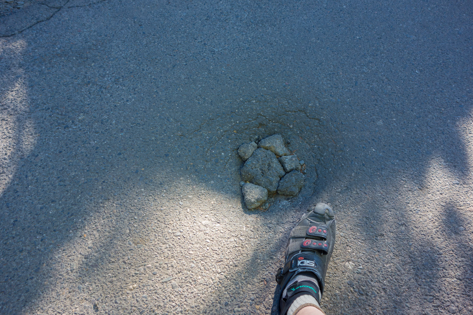 After taking this photo, on my way down the road I succeeded in riding into this dip in the asphalt.  Fortunately, someone had placed some stones in the hole, reducing the severity.
