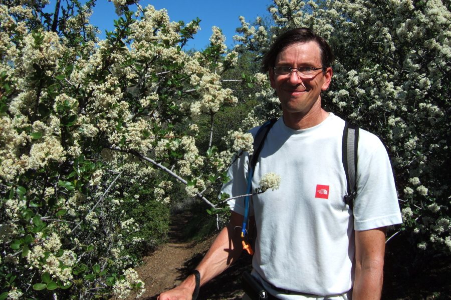 Bill P. stands next to his favorite flowering tree, the ceanothus.