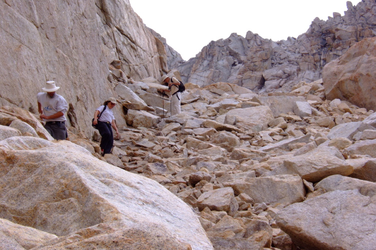 Frank, Stella, and David descend the jumble of rock.