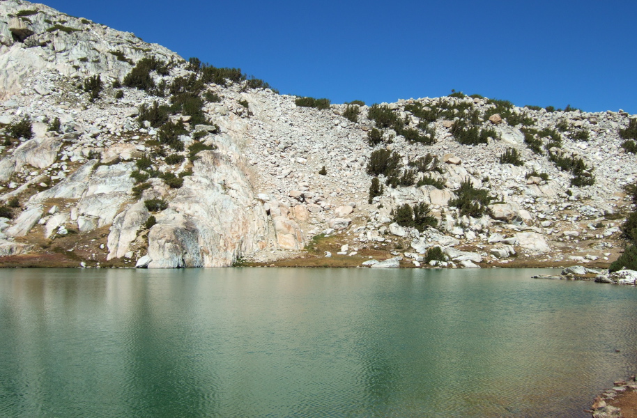 The rock that must be climbed over on the north side of lower Conness Lake.