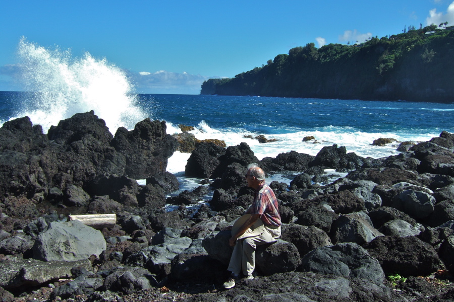 David rests uneasily on a rock before the rough surf at Laupahoehoe Point.