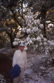 David stands next to a snow-covered madrone tree.