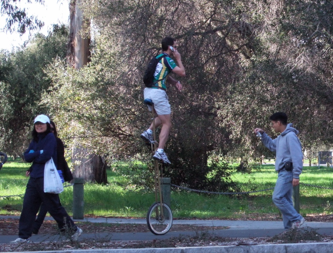 Unicyclist talking on the phone.